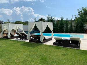 a pool with tents and chairs next to a swimming pool at Theodora Residence in Balatonalmádi