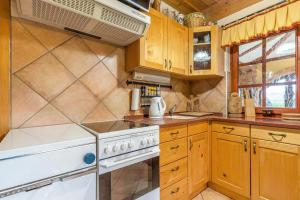 a kitchen with wooden cabinets and a white stove top oven at Forge of Happiness Rustic Retreat - Happy Rentals in Gradac