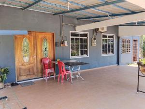 a dining room with a table and two red chairs at Adeeva Homestay Langkawi in Pantai Cenang