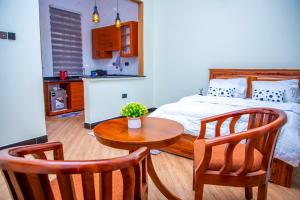 a bedroom with a bed and a table and two chairs at Uhondo Apartments in Dodoma