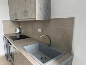 a kitchen with a sink and wooden cabinets at Mykonos Port Apartment in Tourlos