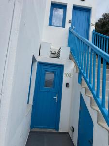 a blue door on a white building with stairs at Mykonos Port Apartment in Tourlos