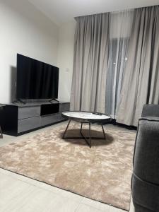 a living room with a table and a flat screen tv at Gate Beautiful in Gaborone +5 photos