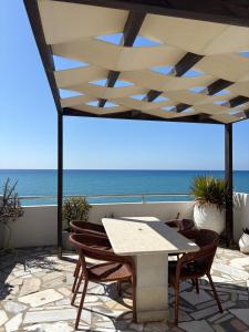 a table and chairs on a patio with the ocean at Blue Sea in Ierapetra +9 photos