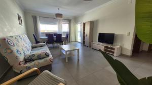 a living room with a couch and a television at Apartamentos Pátio da Aldeia in Armação de Pêra