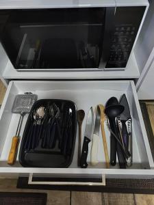 a drawer filled with utensils in a microwave at Espaço aconchegante ótima localização in Foz do Iguaçu