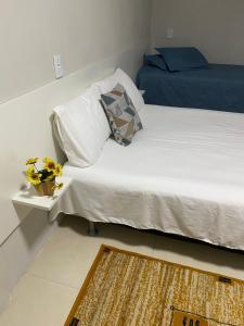 a bed with white sheets and a blue pillow and a rug at Pousada le sorelle in Rosário do Sul