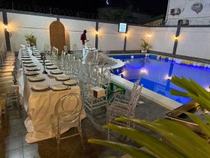 a long table with chairs next to a swimming pool at Hôtel Phoenicia in Brazzaville