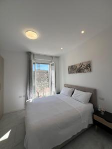 a white bedroom with a large bed and a window at Villa Ibra - Rho Fiera & Milano, Garden & Parking in Paderno Dugnano