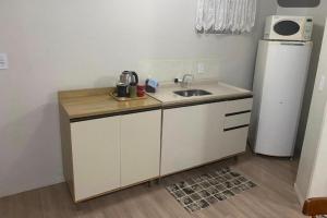 a small kitchen with a sink and a refrigerator at Pousada le sorelle in Rosário do Sul