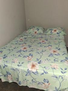 a bed with a floral comforter on it at Pousada Cantinho da Idná in Uberlândia