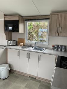 a kitchen with white cabinets and a window at Polls Place in Caernarfon