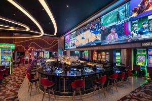 a casino with a bar with red chairs and televisions at Ellis Island Hotel Casino & Brewery in Las Vegas