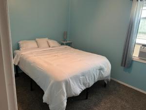 a bedroom with a bed with white sheets and a window at 3 bed room lake cottage in Geneva