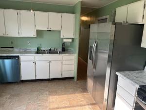 a kitchen with white cabinets and a stainless steel refrigerator at 3 bed room lake cottage in Geneva