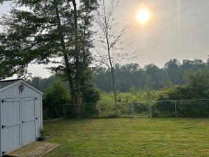a white shed in a yard with a fence at 3 bed room lake cottage in Geneva +3 photos
