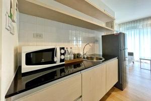 a kitchen with a microwave and a sink at Paeva Luxury By Nakra Functionality in Bang Bo