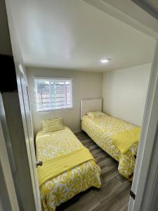 two beds in a small room with yellow sheets at Departamento Nuevo in Tijuana