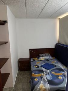 a bedroom with a bed with a blue comforter at Acogedor apartamento en Anapoima in Anapoima
