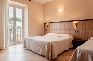 a hotel room with two beds and a window at Hotel Rossi in Manciano