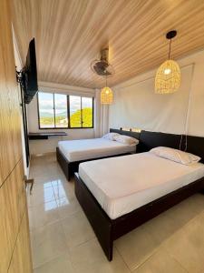 a bedroom with two beds and two windows at Casa Raíces "Aire acondicionado, habitaciones familiares y económicas en La Dorada" in La Dorada