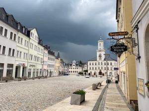 a cobblestone street in a town with a clock tower at Ferienwohnung Goldener Hirsch in Schneeberg