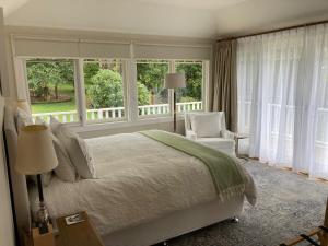 a bedroom with a bed and a chair and windows at Mount Booralee Estate in Blackheath