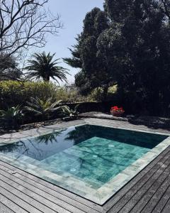 a swimming pool in a yard with a wooden deck at Caloura Suite in Caloura