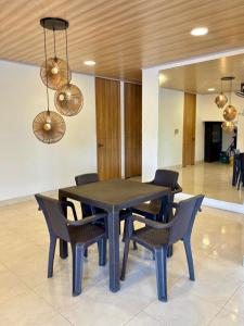 a black dining room table with chairs and chandeliers at Casa Raíces "Aire acondicionado, habitaciones familiares y económicas en La Dorada" in La Dorada +21 photos