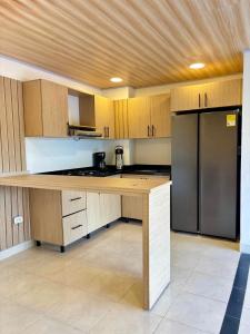 a kitchen with wooden cabinets and a stainless steel refrigerator at Casa Raíces "Aire acondicionado, habitaciones familiares y económicas en La Dorada" in La Dorada
