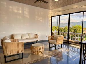 a living room with a couch and chairs and windows at Casa Raíces "Aire acondicionado, habitaciones familiares y económicas en La Dorada" in La Dorada
