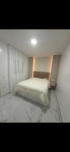 a bedroom with a bed with white sheets and marble floors at Apartamento alhelí 2 in Barbate