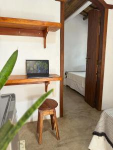 a room with a desk with a laptop on it at Pousada Dendê Caraiva in Caraíva