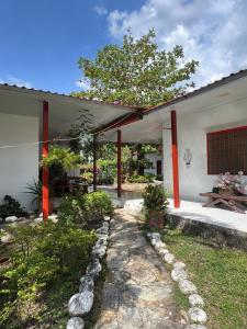 a white house with red pillars and a patio at Finca el milagro Melgar in Melgar