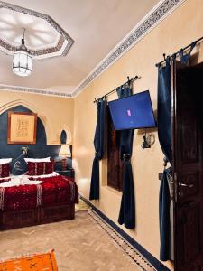 a bedroom with a bed and a tv on the wall at Riad Merzouga in Marrakesh
