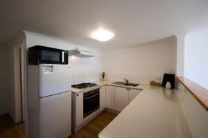 a kitchen with a white refrigerator and a stove at Pine Country Caravan Park in Mount Gambier