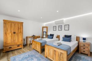 a bedroom with two beds and a dresser at The Green Valley Porto Moniz in Achadas da Cruz