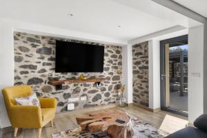 a living room with a tv on a stone wall at The Green Valley Porto Moniz in Achadas da Cruz