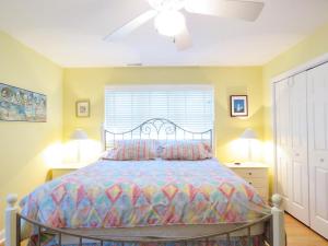 a bedroom with a bed with a colorful comforter and a window at Cedar Cottage in Cape May Point