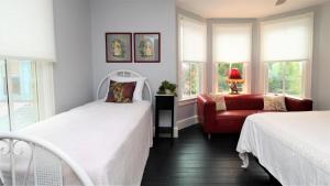 a bedroom with two beds and a red chair at Cottage At 37 Jackson in Cape May