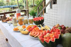 a table topped with plates of fruit and juice at Pousada Recanto do Japa in Nilo Peçanha