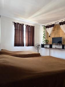 a bedroom with two beds and a fan and a window at Casa Paloma Querida in Taxco de Alarcón