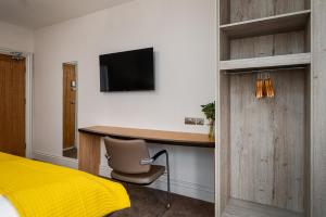 a bedroom with a desk with a chair and a television at Elephant and Castle in Wakefield +19 photos