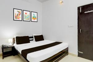 a bedroom with a large bed with white walls at Super OYO Hotel O Indira Nagar in Lucknow