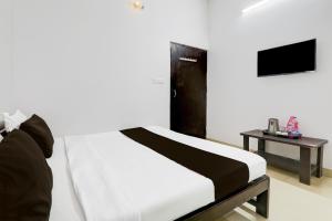 a bedroom with a bed and a tv and a table at Super OYO Hotel O Indira Nagar in Lucknow
