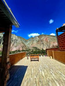a bench on a deck with a view of a mountain at Hostal Nahiara, Iruya in Iruya