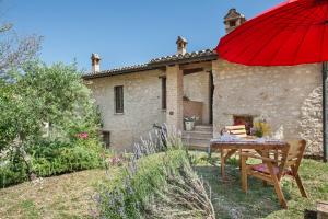 a house with a table and a red umbrella at Casaletto ''La Lavanda'' in Bazzano Inferiore