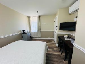 a hotel room with a bed and a desk and a television at Nestle Inn in Hermann