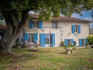 a house with blue shutters and a tree at Lusignac Maswari in Lusignac