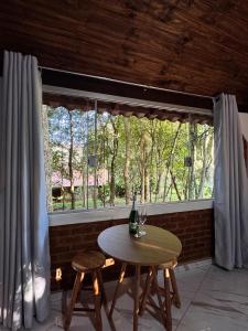 a table and two stools in front of a window at Pousada Árvore Centenária in São Thomé das Letras
